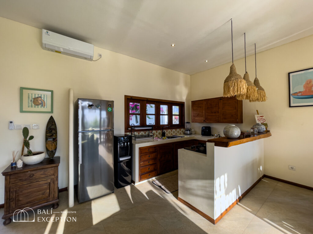 Modern kitchen with wooden cabinets and hanging lights.
