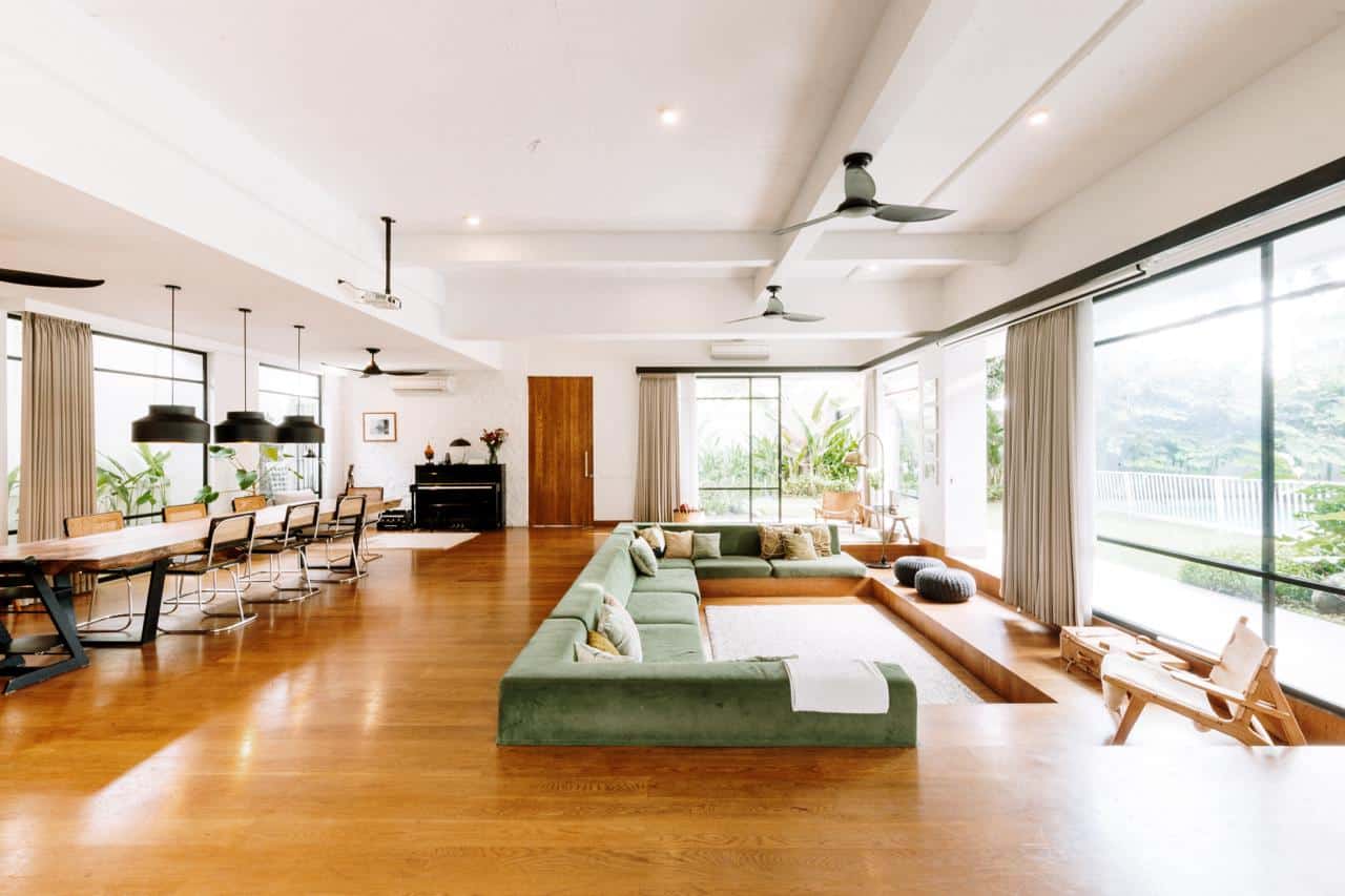 Spacious modern living room with large windows and green sofa.