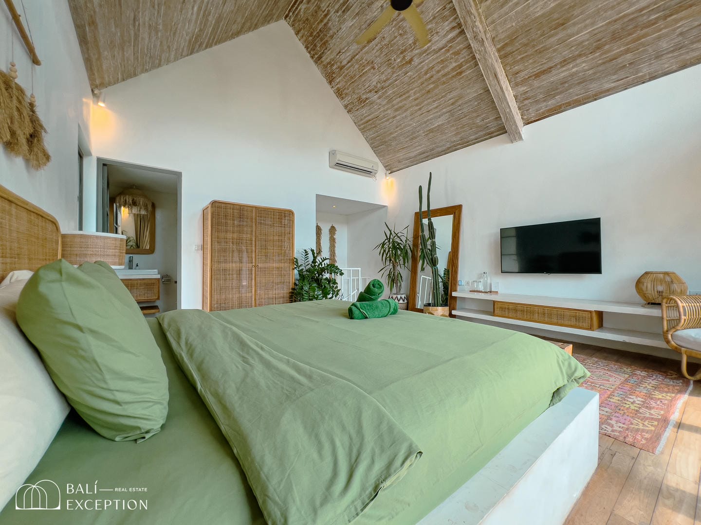 Cozy bedroom with green bedding and wood accents.