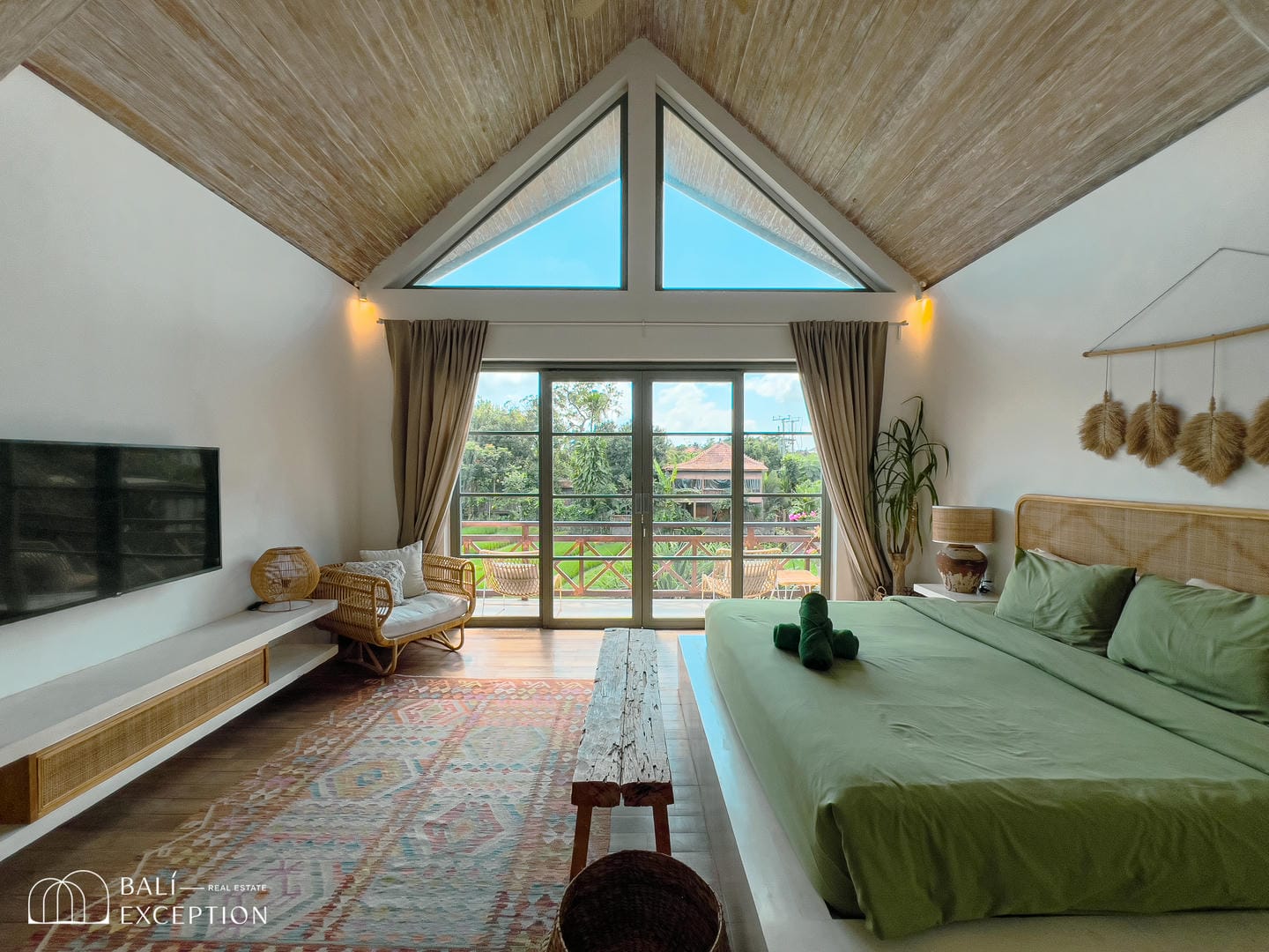 Spacious bedroom with large windows and green accents.