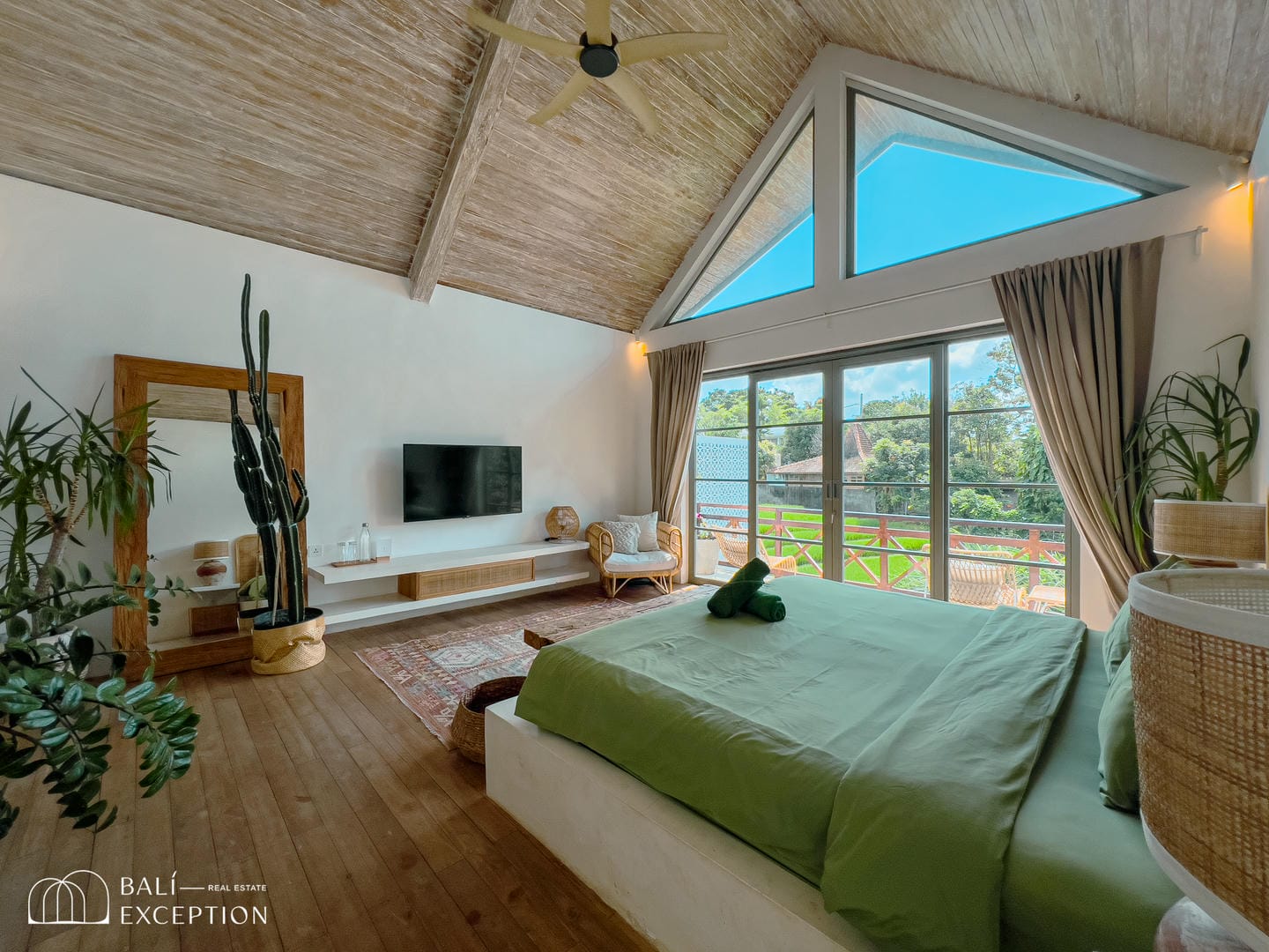 Spacious bedroom with large windows overlooking greenery.