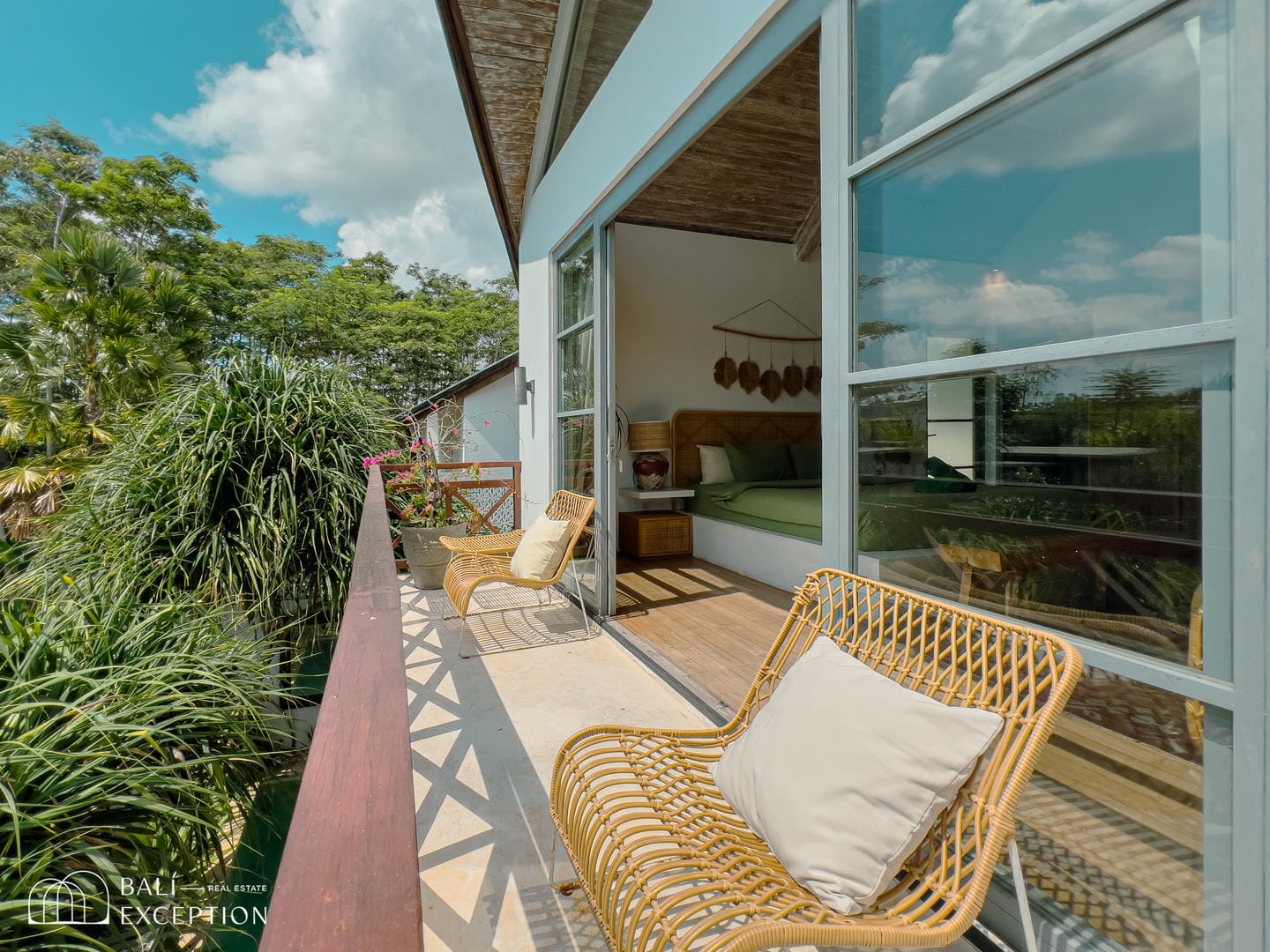 Cozy balcony with chairs and lush greenery view.
