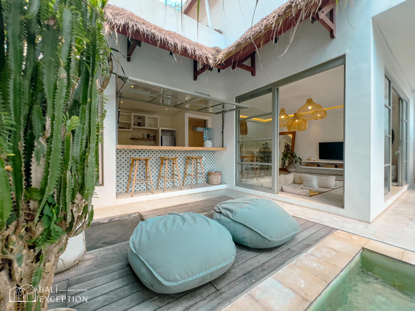 Modern villa with poolside seating and open kitchen.