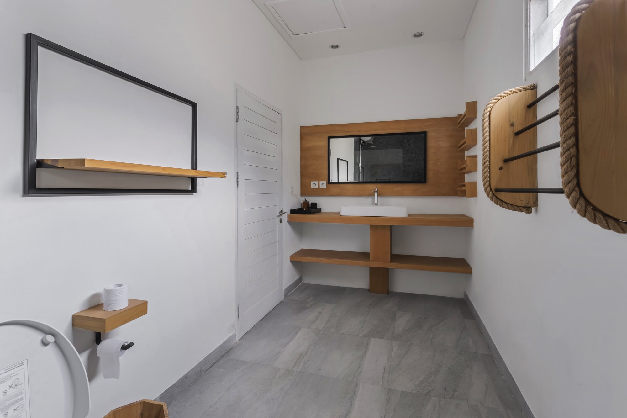Minimalist bathroom with mirror, sink, and wooden shelves.