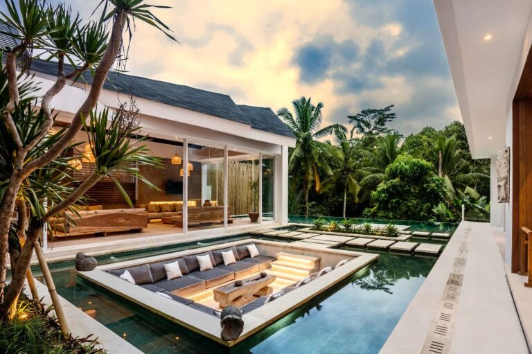 Luxury villa with lush green surroundings and pool.