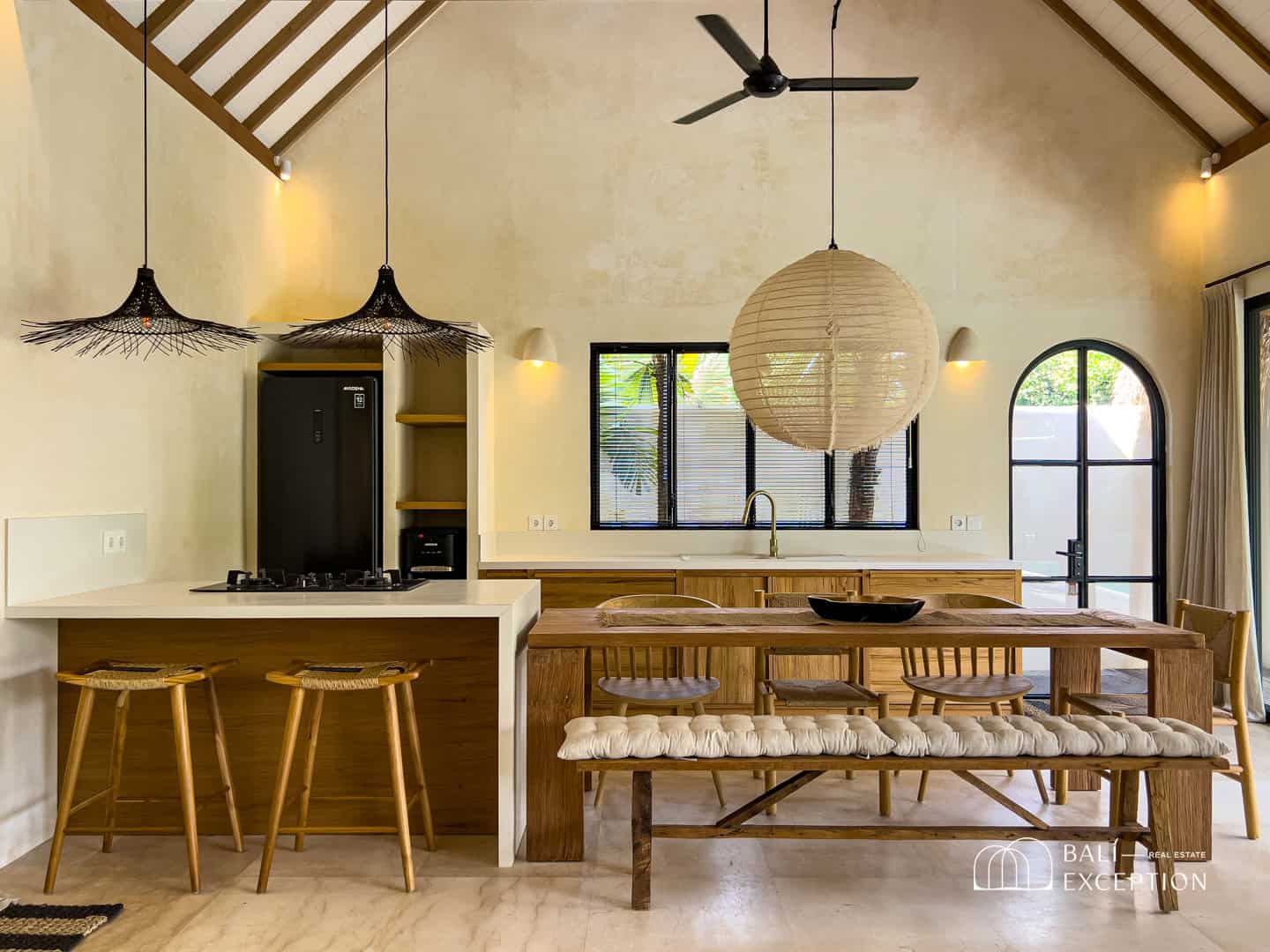 Modern kitchen with wooden furniture and pendant lights.