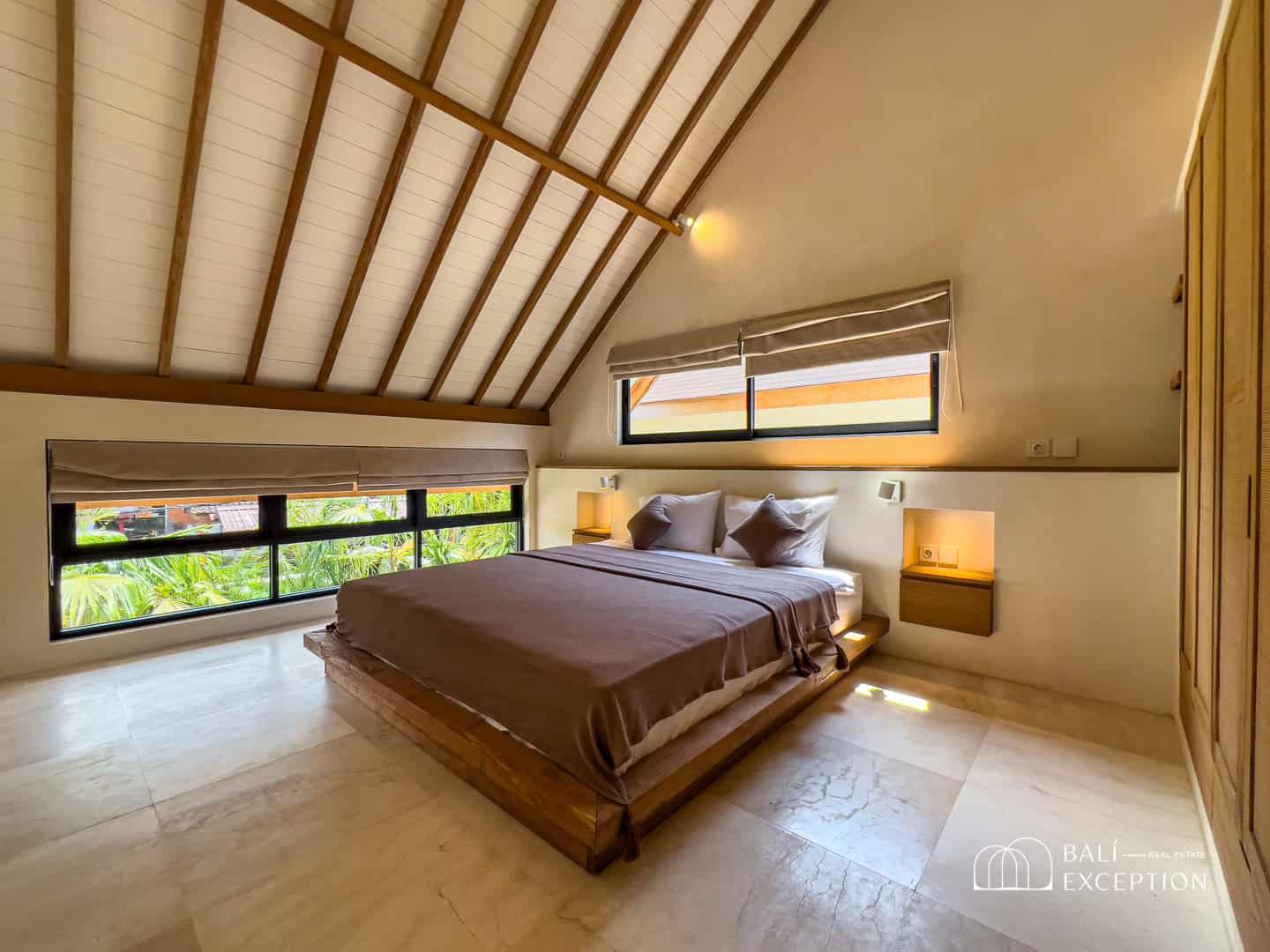 Cozy bedroom with sloped ceiling and large windows.