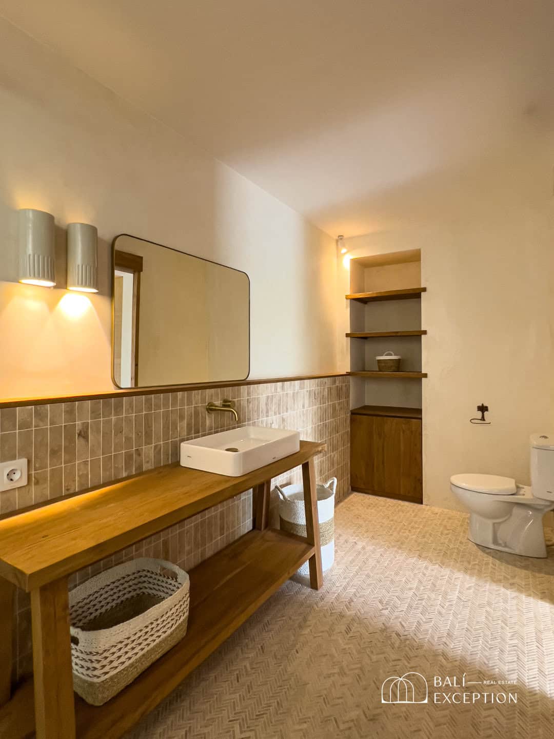 Minimalist bathroom with wooden vanity and tiled walls.