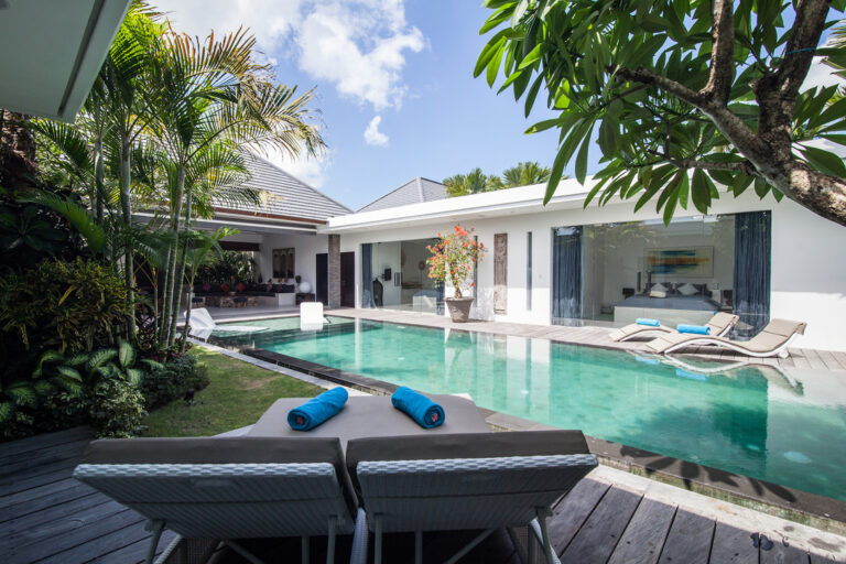 Luxury villa with pool and lounge chairs.