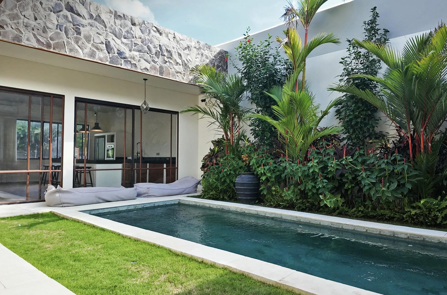 Contemporary patio with pool and lush greenery.