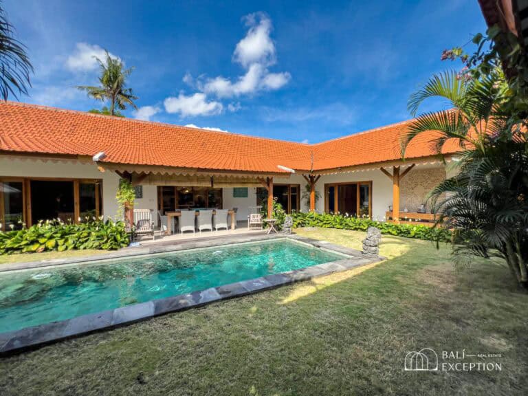 Tropical villa with pool and garden under blue sky.