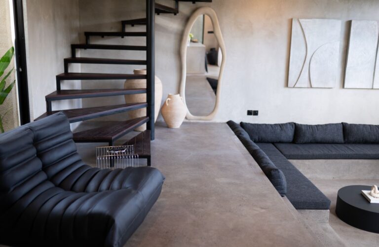 Modern living room with black furniture and staircase.