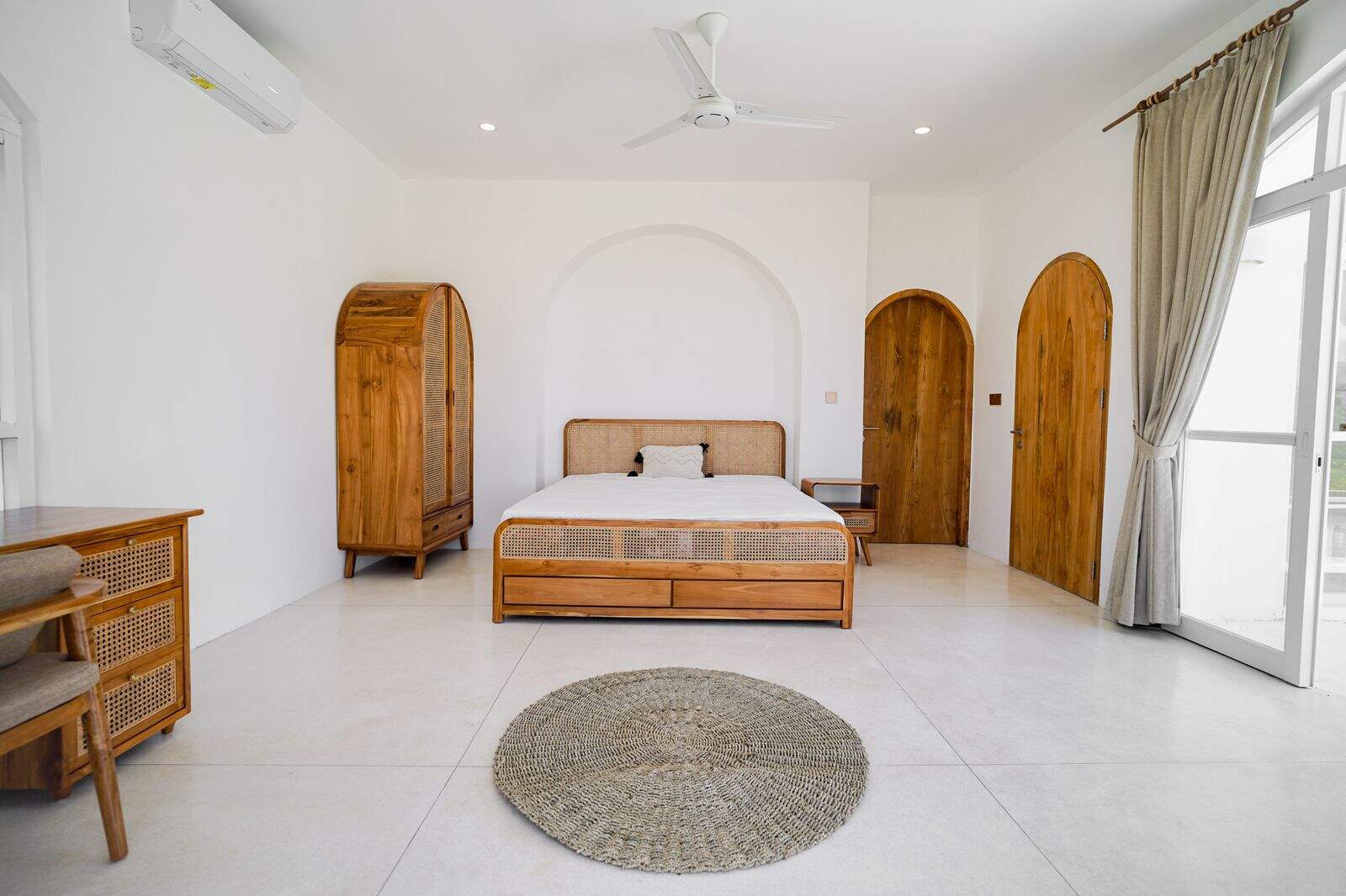 Minimalist bedroom with wooden furniture and woven rug.