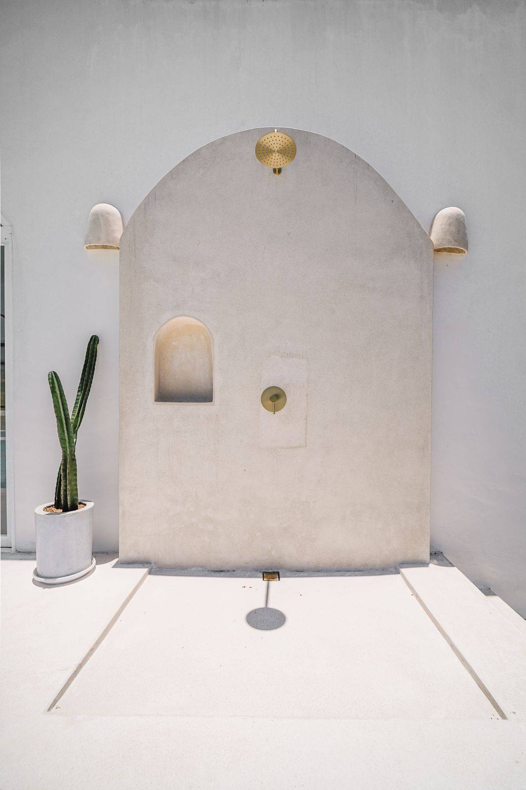 Minimalist outdoor shower with cactus and curved wall