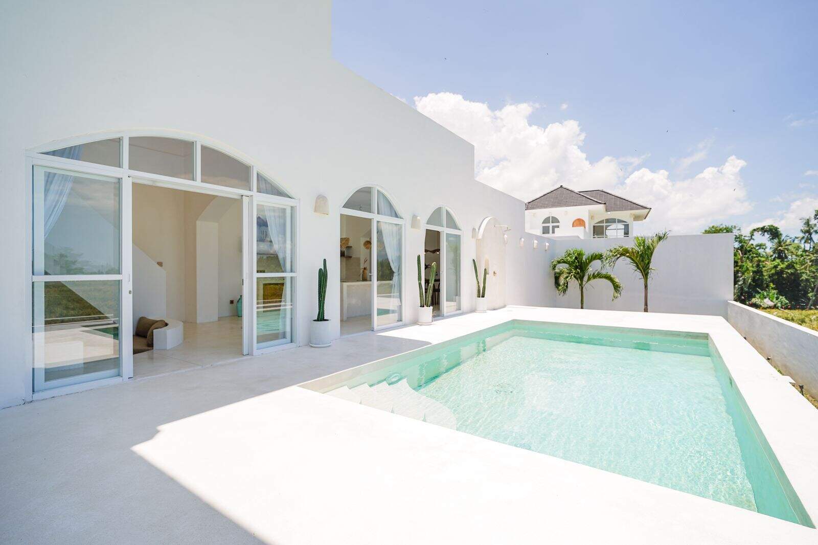 Modern white villa with pool and palm trees.