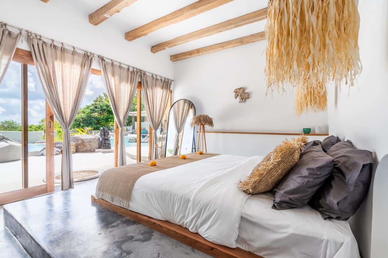 Bright bedroom with pool view and straw decor.