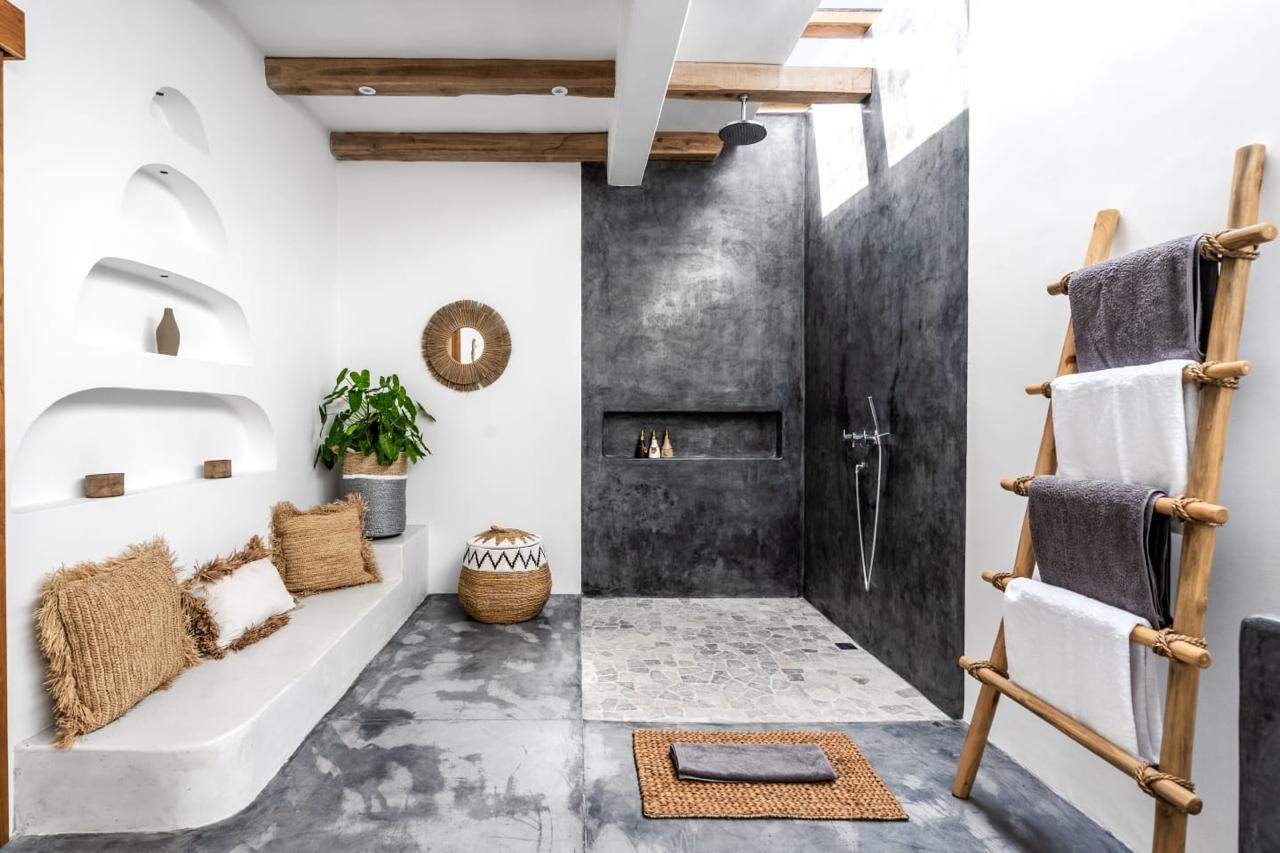 Modern bathroom with gray stone shower and ladder rack.