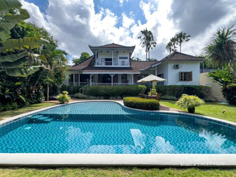 Luxury villa with pool surrounded by lush greenery.