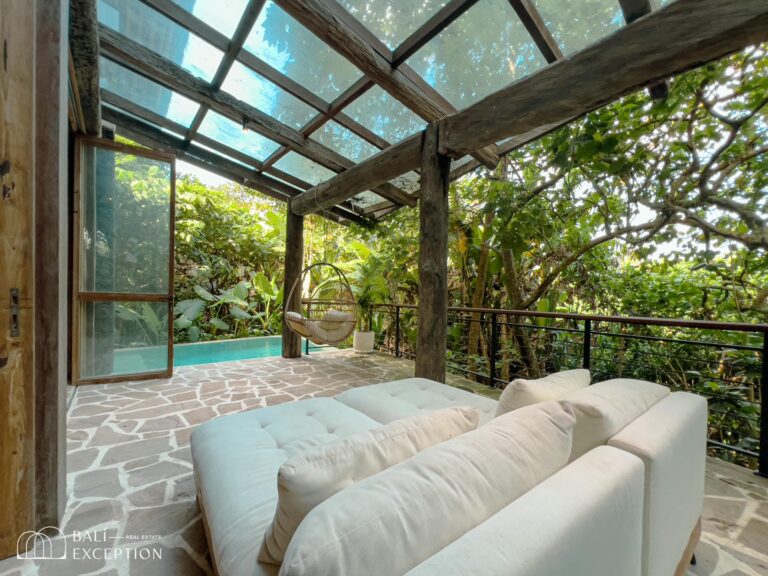 Cozy patio with lush garden and hanging chair.