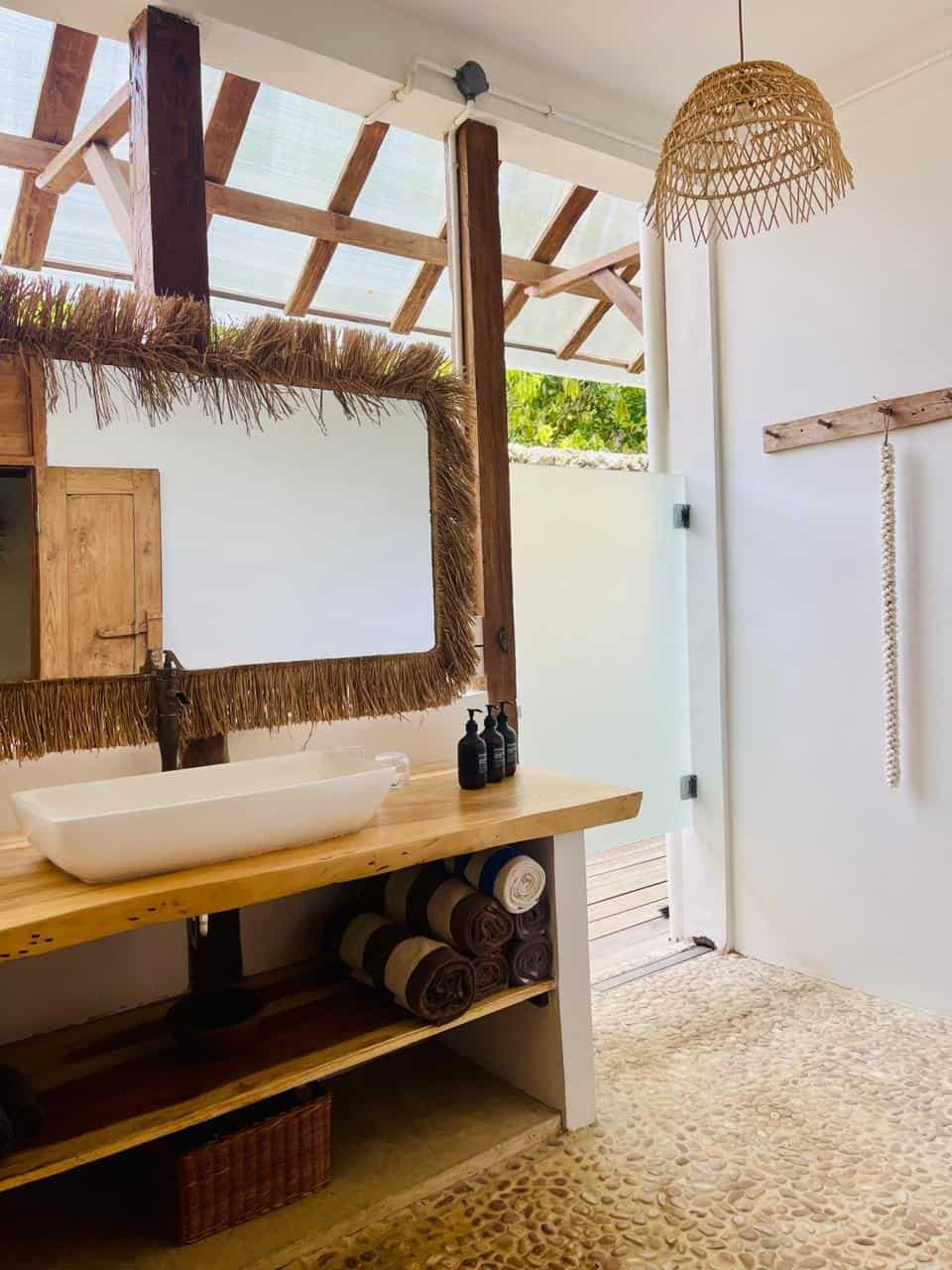 Rustic bathroom with sink, woven lamp, and open door.