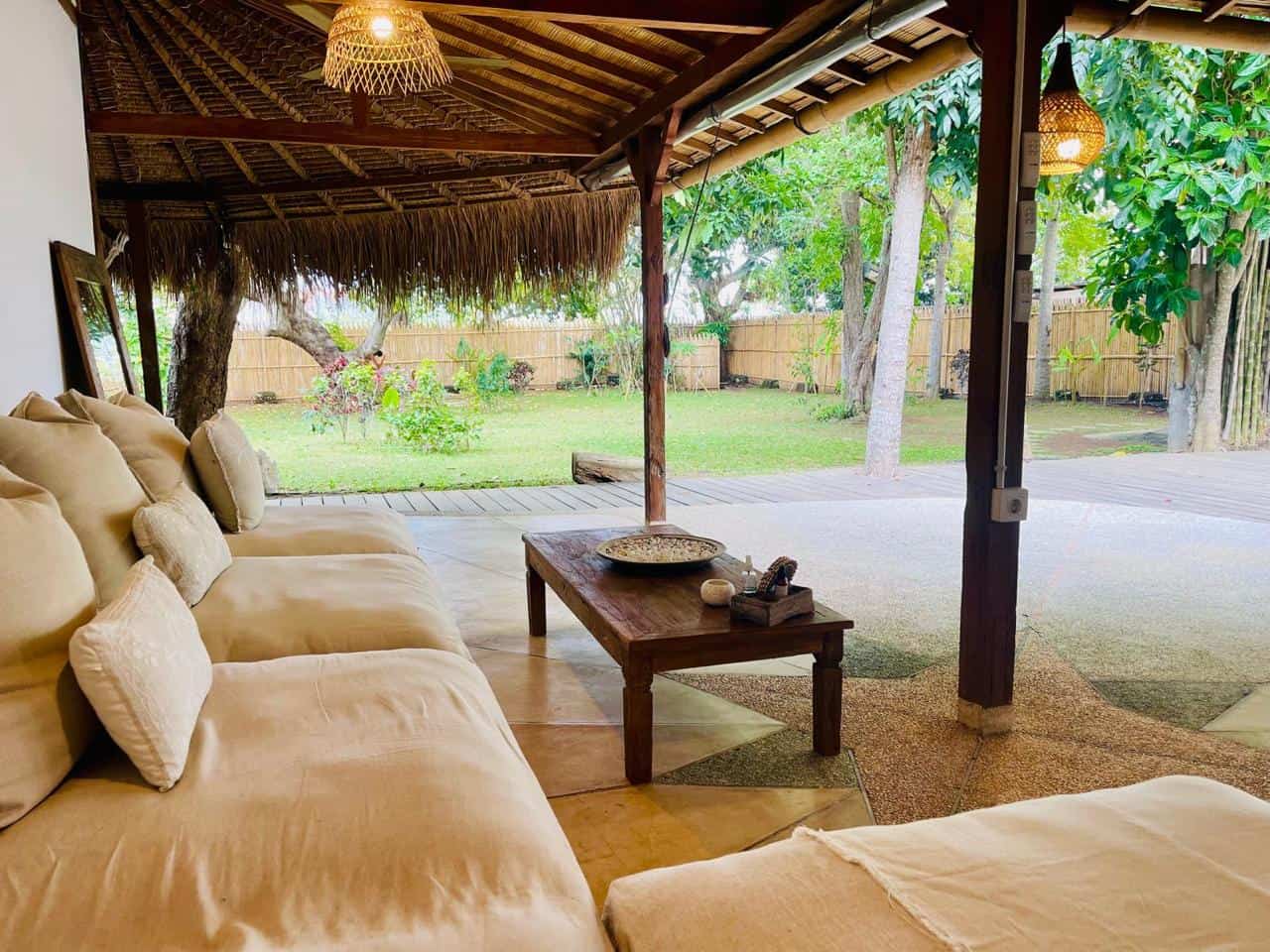 Cozy tropical patio with sofa and garden view.