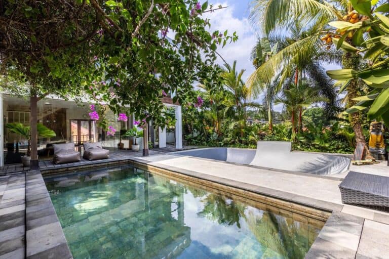 Tropical backyard with pool and lush greenery.