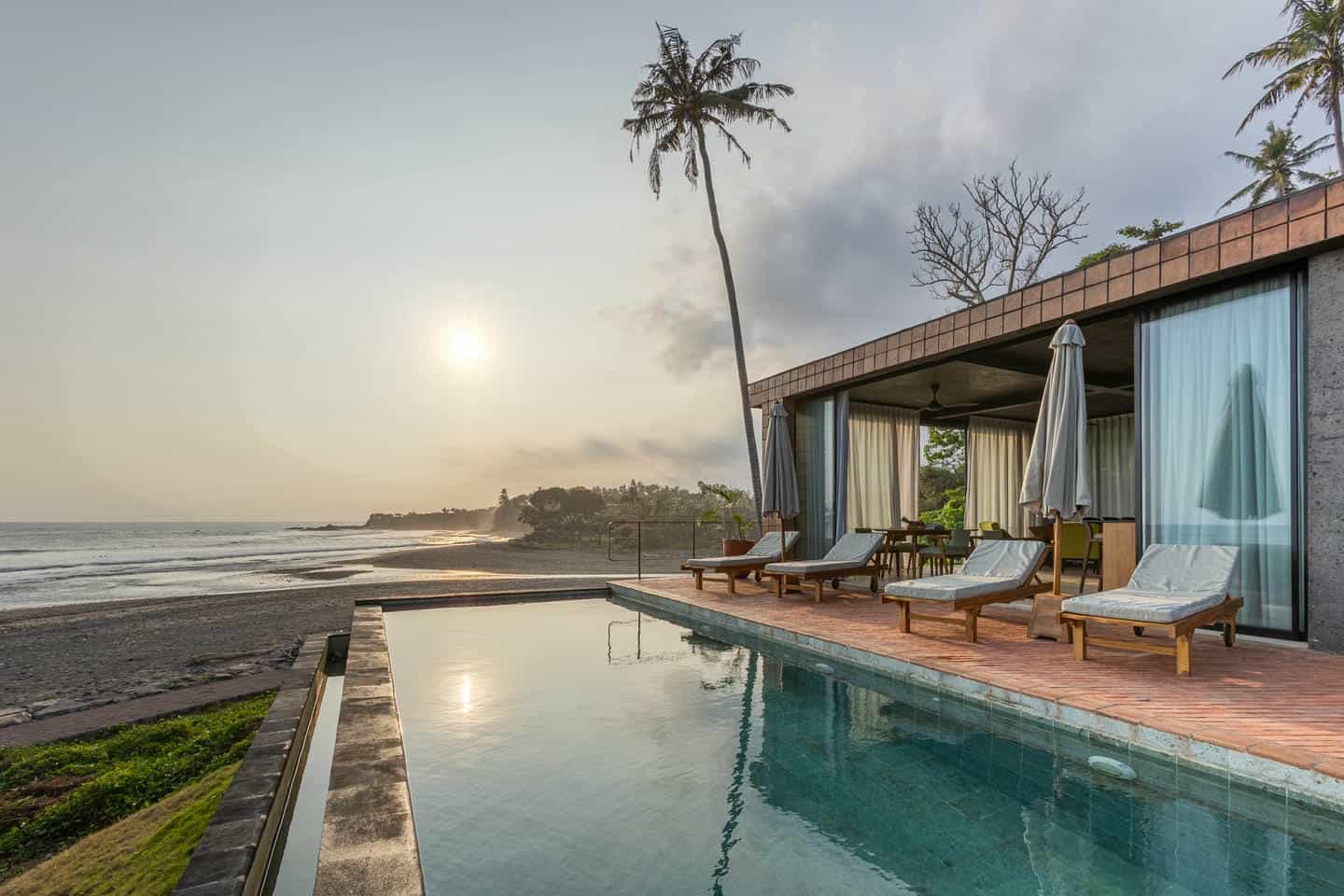 Beachfront villa with pool at sunset view.