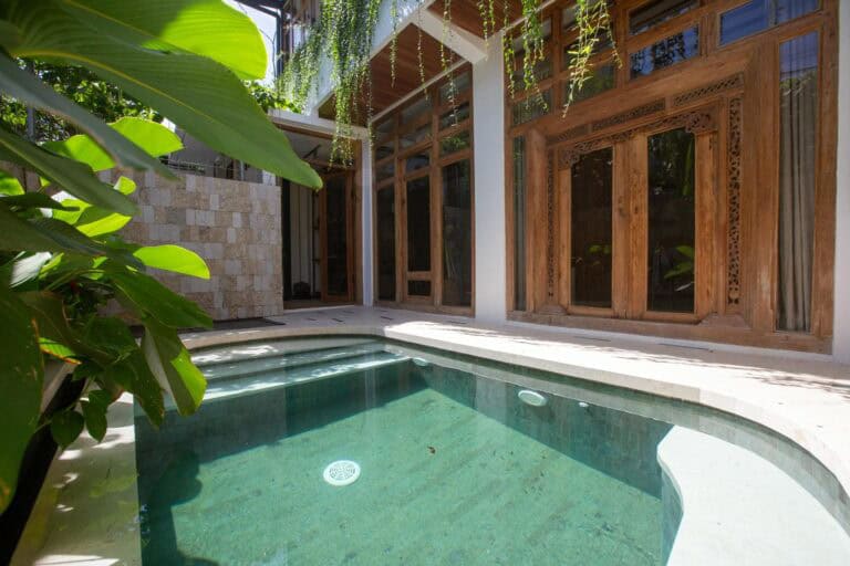 Tropical patio with small pool and wooden windows.
