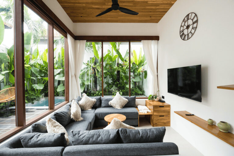 Modern living room with large windows and plants.