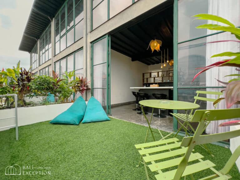 Outdoor patio with seating, grass, and plants.