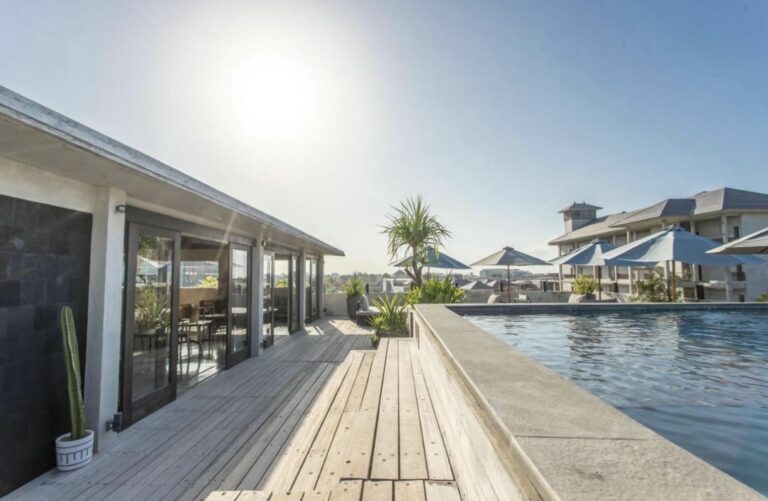 Sunny poolside deck with umbrellas and seating.