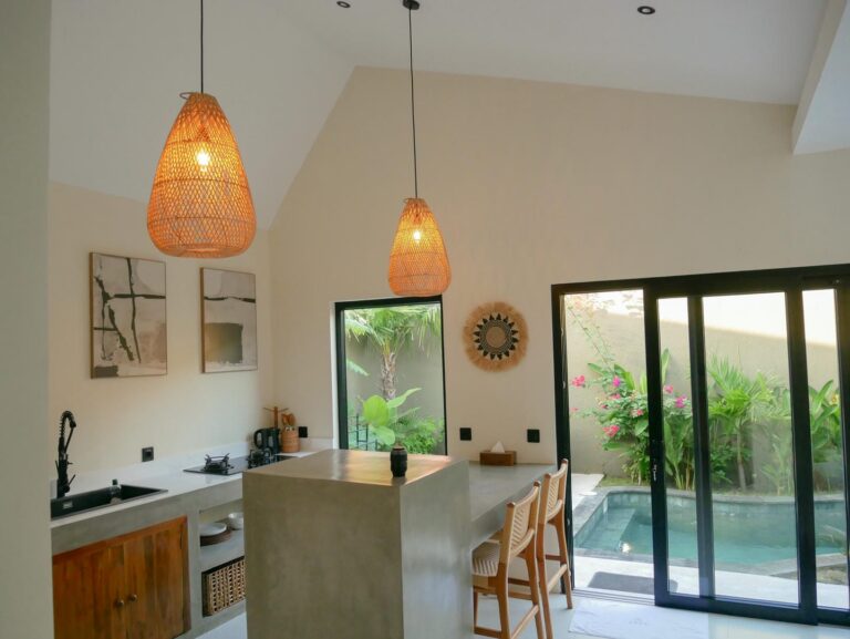 Modern kitchen with island, pendant lights, pool view.