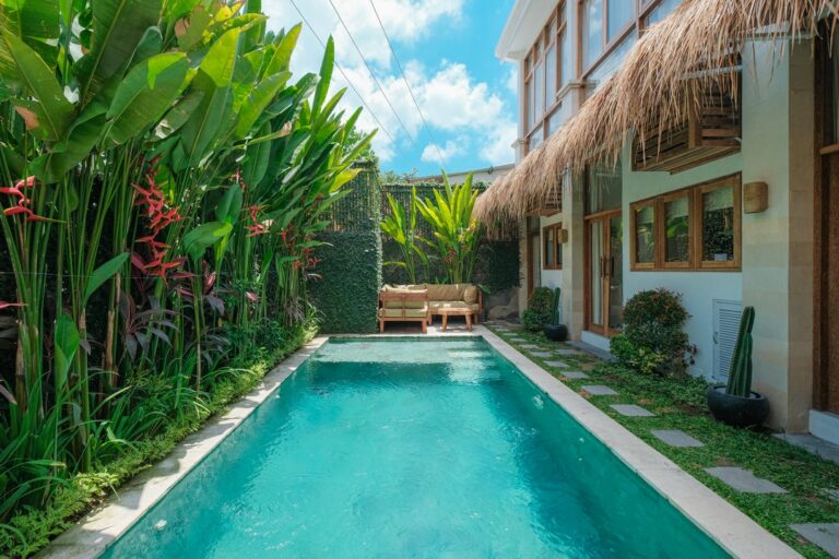 Tropical villa backyard with lush plants and pool.