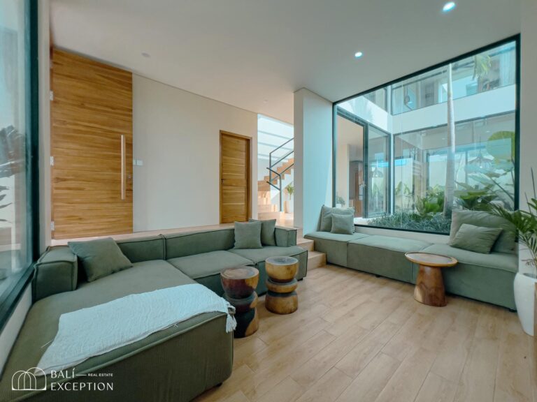 Modern living room with large windows and green sofas.