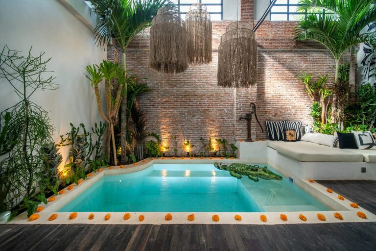 Cozy indoor pool with tropical plants and seating.